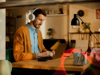 Man working remotely in home office using a laptop and wearing headphones
