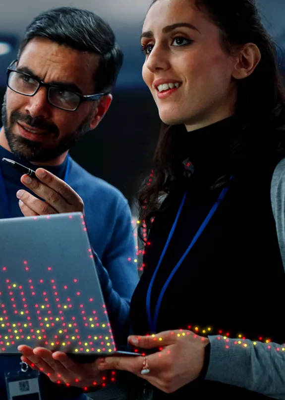 Two engineers with a laptop in a control room 