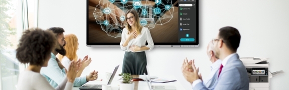 Office workers clapping in meeting room with a presentation on screen and a printer at the side